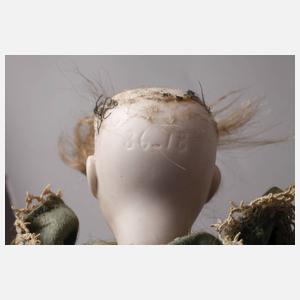 Kleine Porzellankopfpuppe im Seidenkleid