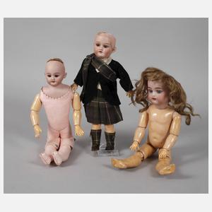 Drei kleine Porzellankopfpuppen mit Kindergesicht
