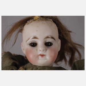 Kleine Porzellankopfpuppe im Seidenkleid