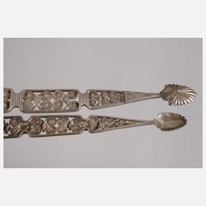 Zwei Zuckerzangen und ein Nadelbehälter