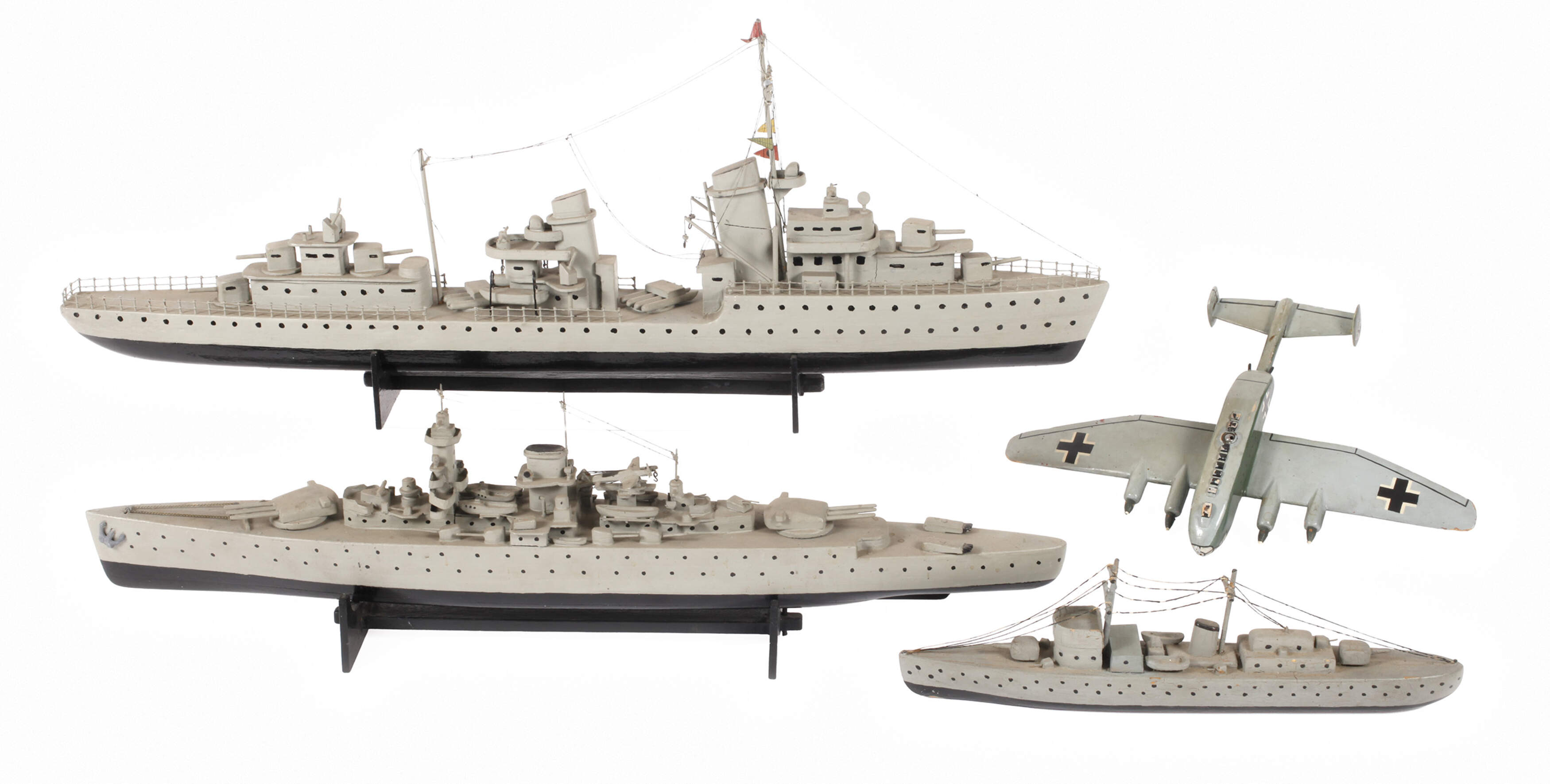 Drei Modell-Kriegsschiffe und Flugzeug