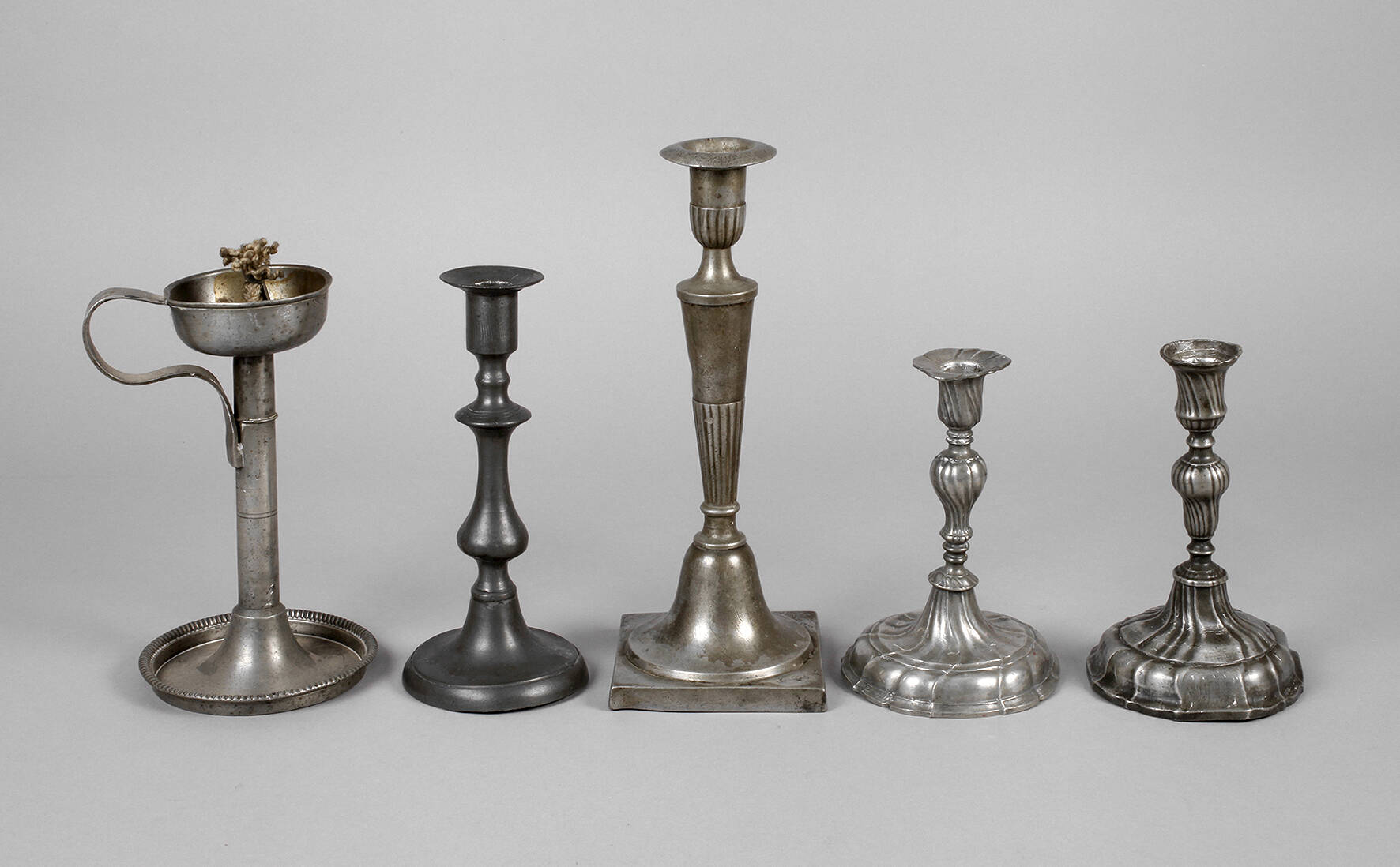 Vier Kerzenleuchter und eine Öllampe