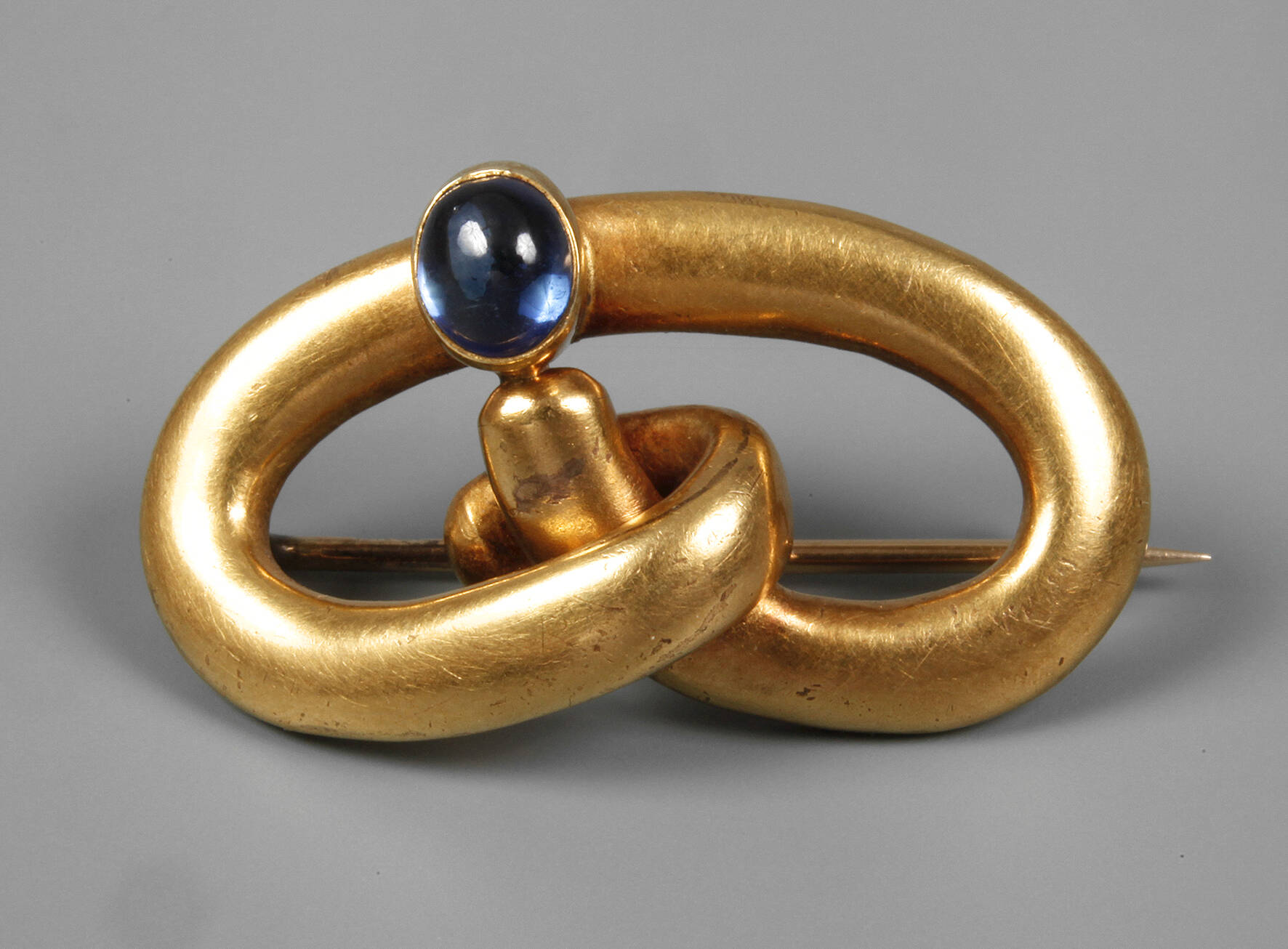 Schleifenbrosche mit Saphir